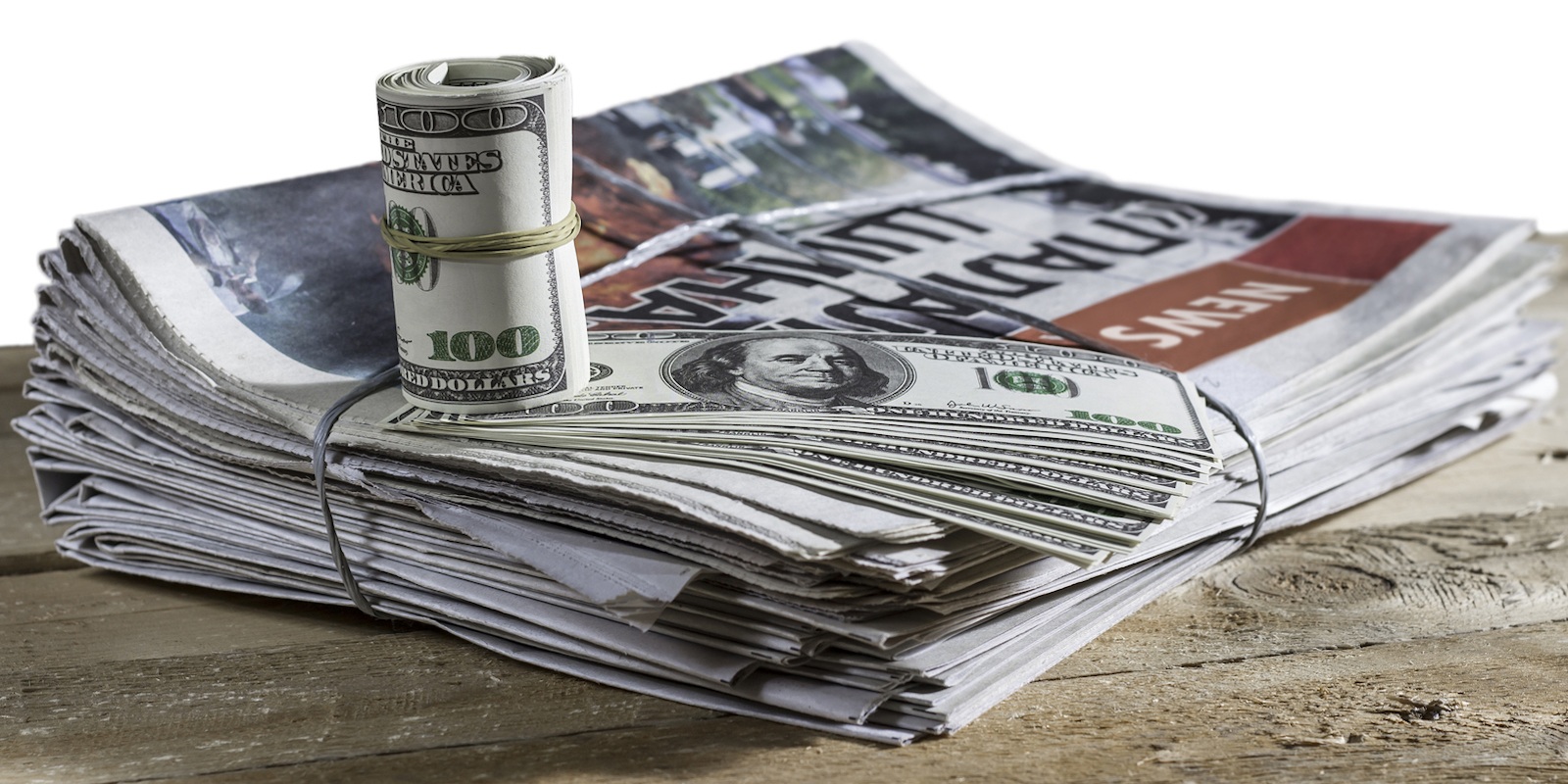 چند عدد روزنامه باطله مرتب روی هم و یک بسته پول رول شده با چند برگه پول دیگر روی روزنامه ها
