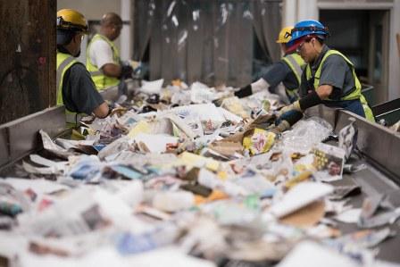 مهمترین مرحله بازیافت کاغذ و مقدار زیادی کاغذ درهم روی نوار نقاله در کارخانه و کارگرانی در حال تفکیک آنها